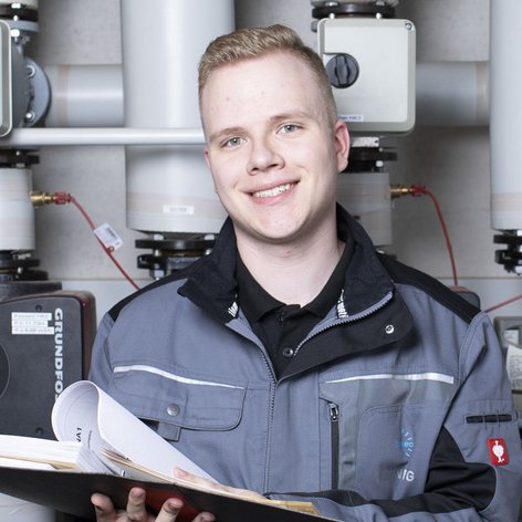 Ein junger Anlagenmechaniker der vor einer Heizungsanlage steht