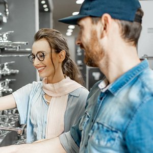 Ein Mann und eine Frau die vor einer Wand mit Sanitaer Armaturen stehen